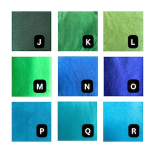 May include: A grid of nine fabric swatches featuring various shades of green and blue. Each square is labeled with a black letter tag from J to R. The textures appear soft and fuzzy, displaying colors ranging from dark forest green to bright cyan.