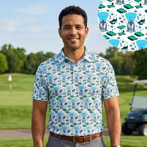 Könnte beinhalten: Ein weißes Poloshirt mit einem sich wiederholenden Muster aus blau-grünen roboterartigen Figuren und Landschaftselementen. Das Shirt hat einen Kragen und kurze Ärmel. Die Person trägt eine graue Hose und einen braunen Gürtel.
