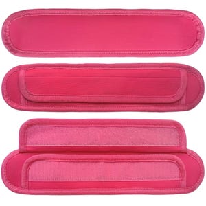 May include: Three pink fabric straps with velcro closures. The straps are designed to be used as shoulder pads for bags or backpacks.