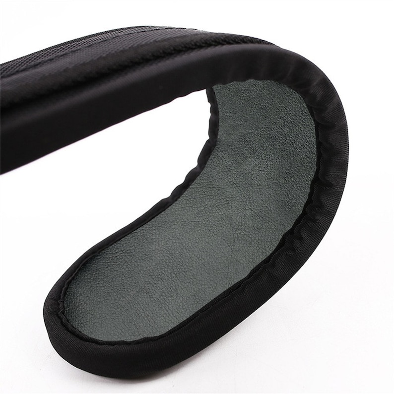 May include: Black padded camera strap with a gray leather-like lining. The strap is designed to provide comfort and support for carrying a camera.