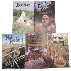 May include: A collection of vintage books with titles like "Buckskin," "Fire & Candage," "Makin' Meat," and "Wilderness Cooking." The covers feature illustrations of outdoor survival skills, including bow and arrow use and cooking.