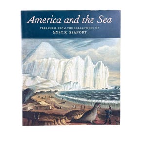 May include: A hardcover book titled "America and the Sea" with a blue cover and a vintage illustration. The illustration depicts a coastal scene with a large iceberg, figures, and a seal. The text "Treasures from the Collections of Mystic Seaport" is also visible.