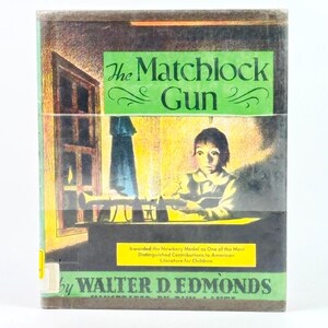 May include: A vintage book cover for "The Matchlock Gun" by Walter D. Edmonds. The cover features a green title banner with the book's title. The illustration shows a child in a room with a window and a gun. A yellow banner states the book won the Newbery Medal.