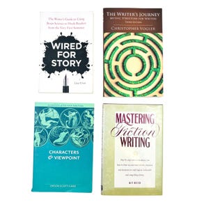 May include: Four books on writing: Wired for Story by Lisa Cron with a black ink splatter design, The Writer's Journey by Christopher Vogler featuring a green maze, Characters & Viewpoint by Orson Scott Card in teal, and Mastering Fiction Writing by Kit Reed.