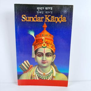May include: A book cover with a blue background and a depiction of a Hindu deity with a crown and a bow and arrow. The title of the book is "Sundar Kanda" in Hindi.