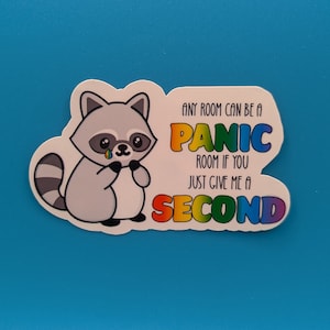 Könnte beinhalten: Ein Aufkleber mit einem Cartoon-Waschbären mit einer Regenbogen-Träne und dem Text "Any room can be a panic room if you just give me a second".
