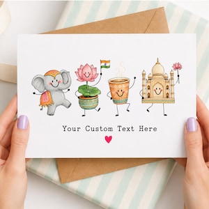 May include: A white greeting card featuring four cartoon characters: a gray elephant, a pink lotus flower in a pot holding an Indian flag, a steaming cup of tea, and the Taj Mahal holding a flower. The text reads Your Custom Text Here with a red heart.