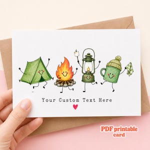 May include: A greeting card featuring a watercolor illustration of a smiling green tent, a campfire, a lantern, and a green mug with a beanie, all with stick arms and legs. The text "Your Custom Text Here" is printed above a small red heart.
