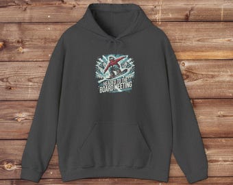May include: Dark gray hooded sweatshirt with a graphic of a snowboarder in a red jacket and the text "Headed to the Board Meeting".