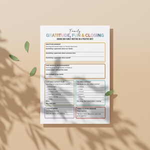 Op de afbeelding: Een witte, afdrukbare gezinsvergaderagenda met de woorden "Family, GRATITUDE, FUN & CLOSING" bovenaan. De agenda bevat secties voor dankbaarheid, vriendelijke woorden, een leuk activiteitenplan en een gevoelencheck-in. Groene bladeren zijn verspreid.