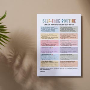 May include: A white paper with the title "Self-Care Routine" in colorful text. The paper lists 12 self-care practices, including hygiene, healthy eating, and expressing feelings. The text is in a sans-serif font.