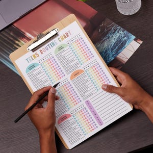 Puede incluir: Un portapapeles de madera con una "TEENS ROUTINE CHART" impresa en colores pastel. El gr&aacute;fico incluye secciones para las rutinas de la ma&ntilde;ana, las tareas diarias, los h&aacute;bitos y las rutinas de la noche. Una persona sostiene el portapapeles y un bol&iacute;grafo.