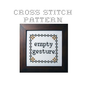 Può includere: Schema di punto croce in una cornice marrone con tessuto bianco e ricamo nero. Lo schema recita "empty gesture" con piccoli fiori marroni negli angoli.