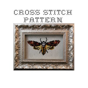 May include: Cross stitch pattern of a moth with a skull design on its wings. The moth is framed in a silver ornate frame.