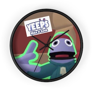 May include: A black wall clock with a colorful image of a blue character with a red headband. The character is giving a thumbs up. The clock face has black hands and a white background. The clock has a white label with the text "YEEPS Hide & Seek".