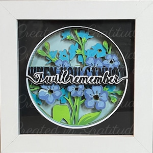 May include: A framed paper craft with blue flowers and green leaves. The text "When you cannot I will remember" is in black lettering.