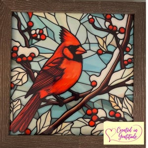May include: A framed stained glass artwork featuring a vibrant red cardinal perched on a branch with red berries and white snow. The background is a mosaic of blue and white shapes, with a brown wooden frame.