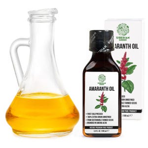 Può includere: Una caraffa di vetro trasparente e una bottiglia marrone di olio di amaranto Siberian Green. La bottiglia ha un'etichetta bianca con le parole "AMARANTH OIL" e un grafico della pianta di amaranto. La caraffa è piena di olio dorato.