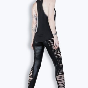 May include: A black sleeveless tank top with a distressed back and a pair of black leggings with cutouts on the sides. The leggings are worn with black platform shoes.