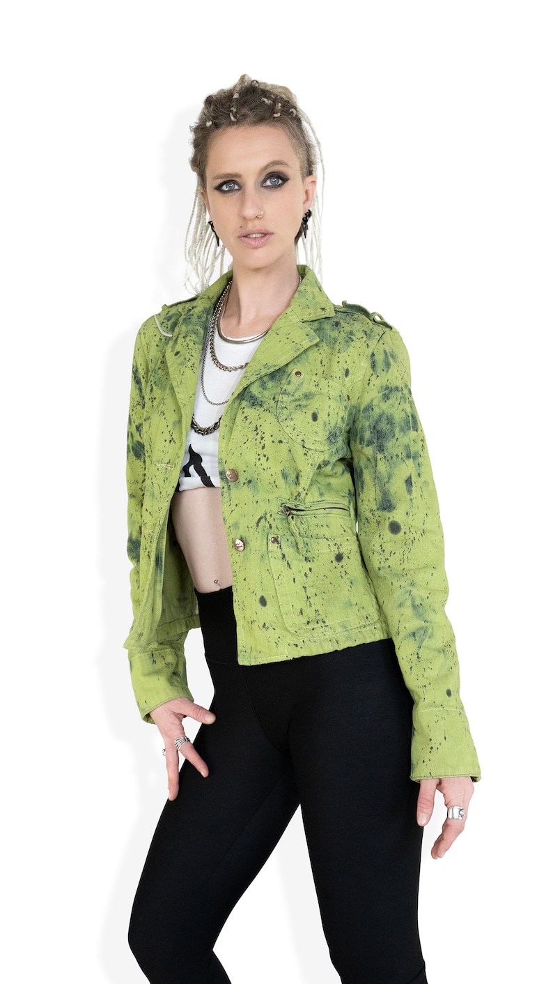 May include: A green splatter-painted denim jacket with a zippered pocket and button closure.