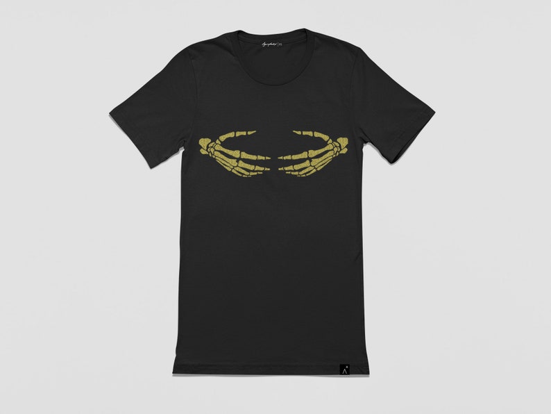 May include: Black t-shirt with a gold skeleton hand graphic on the front. The hands are facing each other and appear to be holding something.