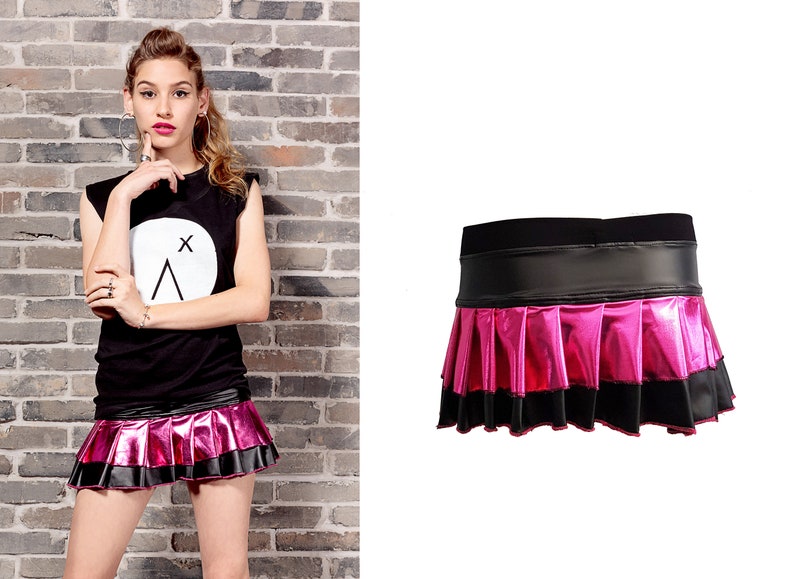 May include: A pink and black mini skirt with a pleated design and a black waistband. The skirt is made of a shiny, metallic fabric.