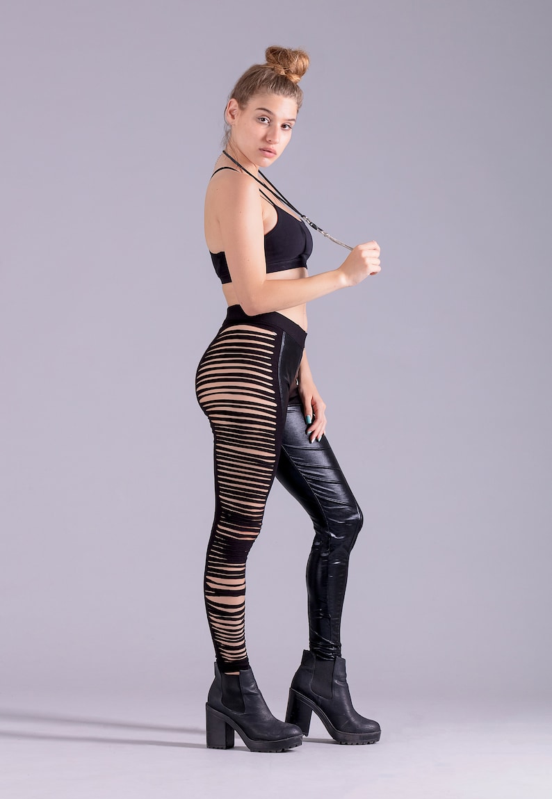May include: A woman wearing a black sports bra and black leggings with cutouts. She is wearing black heeled boots and has her hair pulled back in a bun.