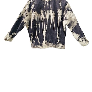 May include: A denim jacket with a unique tie-dye pattern in shades of black and white. The jacket features a classic collar, button-down front, and long sleeves. The tie-dye design creates a striking visual effect, making it a standout piece.