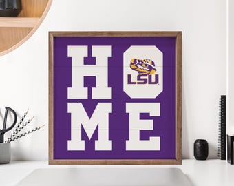 May include: Wooden framed sign with the word "HOME" in large white letters on a purple background. The "O" is replaced with the LSU logo. The sign is displayed on a white surface.