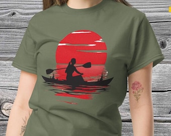 Puede incluir: Una camiseta verde con la silueta de una persona en una canoa remando hacia una puesta de sol roja. La canoa está en una masa de agua con árboles en el fondo.