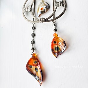 Lampwork butterfly wings in orange dangle from this statement necklace