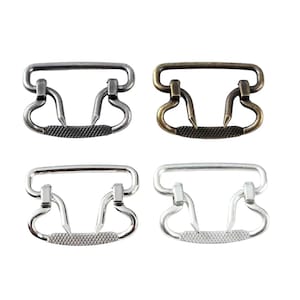 Pode incluir: Quatro fechos de metal em diferentes acabamentos: prata, latão antigo, níquel e níquel polido. Cada fecho tem uma barra superior retangular e duas alças em forma de coração.