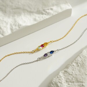 May include: Two delicate bracelets with a pea pod design. One bracelet is gold with blue, green, red, and yellow gemstones. The other bracelet is silver with purple, white, and blue gemstones.