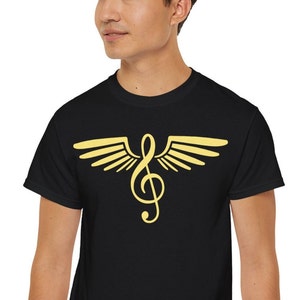 May include: Black t-shirt featuring a gold treble clef design with stylized wings. The musical symbol is centered on the chest. The shirt is made of a soft material.