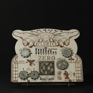 May include: A wooden game board for a cleric character in a tabletop role-playing game. The board features a hand-drawn image of a cleric with the word "CLERIC" above it. The board has several dials and counters for tracking hit points, spell slots, and other stats. The board is labeled "ZERO" in the center.