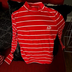 May include: Red and white striped long-sleeve shirt with a mock neck and the letters "ΔΣΘ" embroidered on the front.