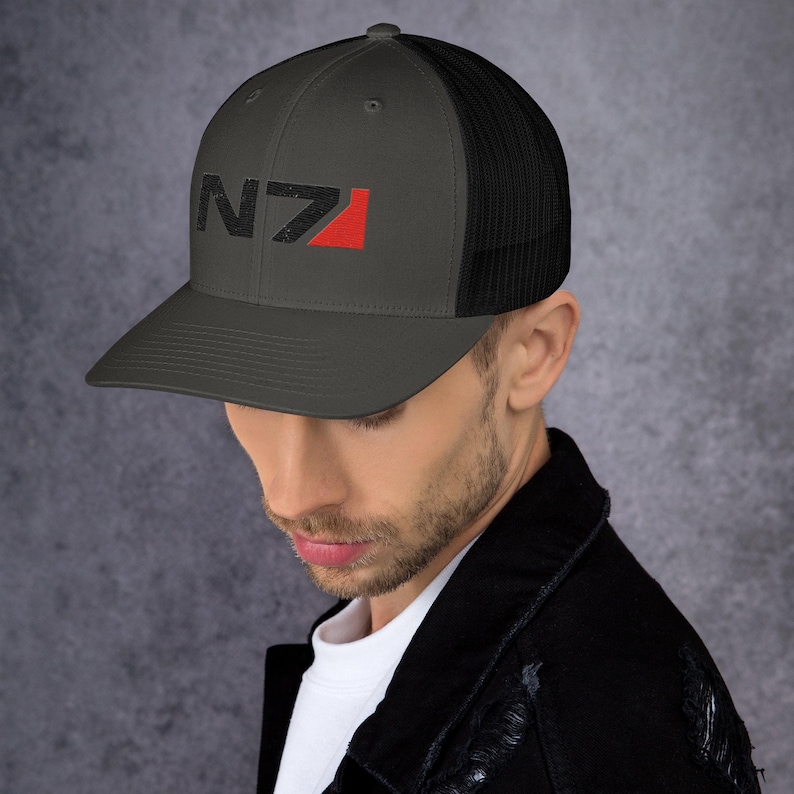 May include: A dark gray and black trucker hat with a red and black N7 logo embroidered on the front.