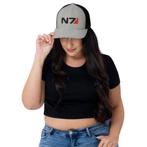 May include: A gray and black trucker hat with a black and red "N7" logo embroidered on the front.