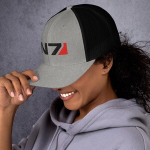 May include: A gray and black trucker hat with a black and red N7 logo embroidered on the front.