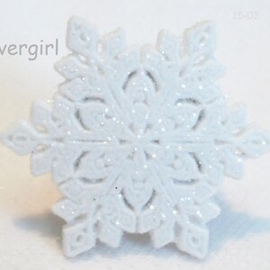 May include: White snowflake ornament with a glittery finish. The snowflake has a detailed design and is perfect for adding a touch of winter magic to your home decor.