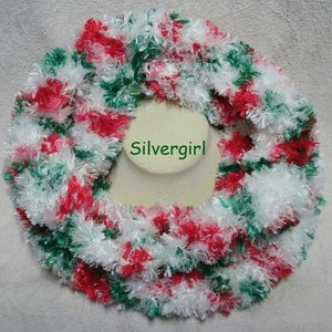 May include: A white, red, and green fuzzy scarf. The scarf is displayed on a white mannequin bust. The text "Silvergirl" is visible on the bust.