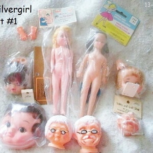 May include: A set of doll parts, including heads, bodies, and hands. The doll parts are made of plastic and are in various colours, including pink, white, and brown. The set is labelled "Silvergirl Set #1".