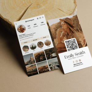 May include: Two business cards with travel-themed branding. One card displays a social media profile with travel photos. The other card features a woman in a hat and a QR code, with the name "Emily Smith, Travel Agent, California."