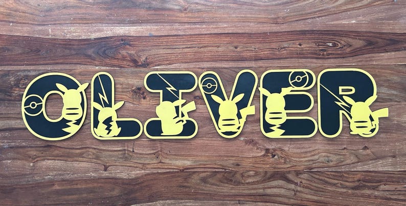 May include: Black and yellow wooden letters spelling the name "OLIVER" with a Pikachu character design on each letter.