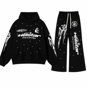 May include: A black hooded sweatshirt and matching wide-leg sweatpants set featuring white graphic prints of stars, flames, and the text Hellstar Faith to Stardom. The hoodie has long sleeves and the pants include a white drawstring at the waist.