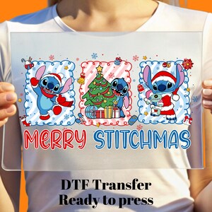 May include: A clear DTF transfer featuring the character Stitch in Christmas attire. The design includes Stitch with a Santa hat, a Christmas tree, and the text "MERRY STITCHMAS". The words "DTF Transfer Ready to press" are also included.