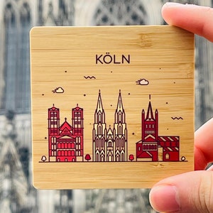 Könnte beinhalten: Ein Holz-Untersetzer mit einer roten und weißen Illustration des Kölner Doms und dem Text "KÖLN" in rot.