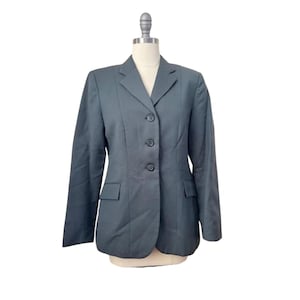 May include: A dark gray blazer with a notched lapel, three-button closure, and two front pockets. The long-sleeved jacket is displayed on a mannequin against a white background. The blazer is a classic, tailored style.