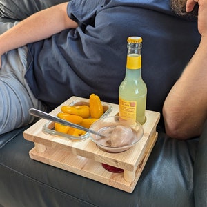 Könnte beinhalten: Ein Tablett aus Holz mit drei Fächern, eines mit gelben Paprika gefüllt, ein anderes mit einer kleinen Schüssel Schokoladenpudding und das dritte mit einer Flasche klarem, gelbem Getränk.