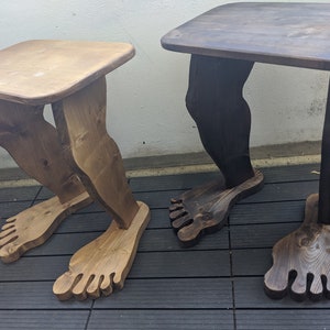 Peut inclure: Deux tables en bois avec des pieds en forme de jambes humaines. Une table est brune et l'autre est brun clair.